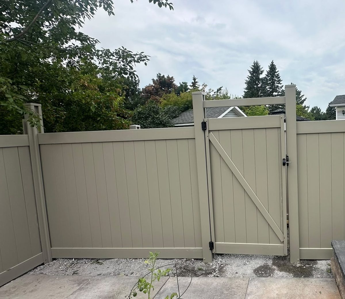 A single Adobe PVC gate hung between two posts, with a diagonal brace across it and a latch on the far side.